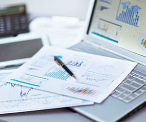 workdesk with laptop and documents showing bar graphs and charts