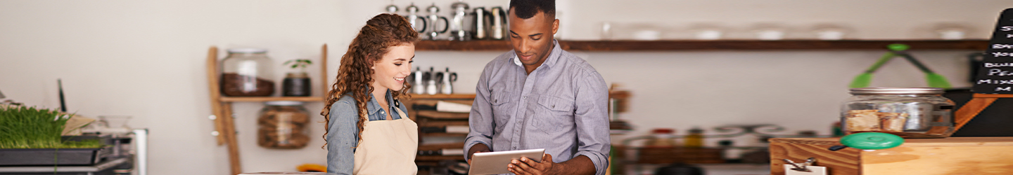 two workers in a restaurant setting looking at reports on an ipad