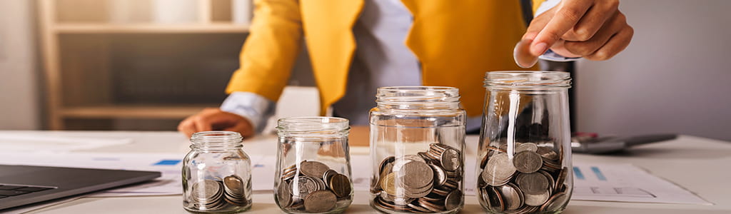 four jars in incremental sizes with US coins in them