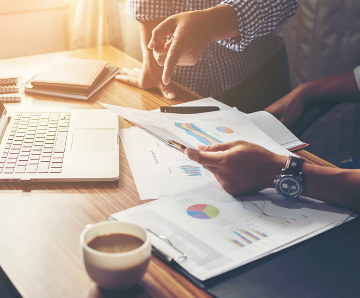 two people collaborating around paper charts and laptop