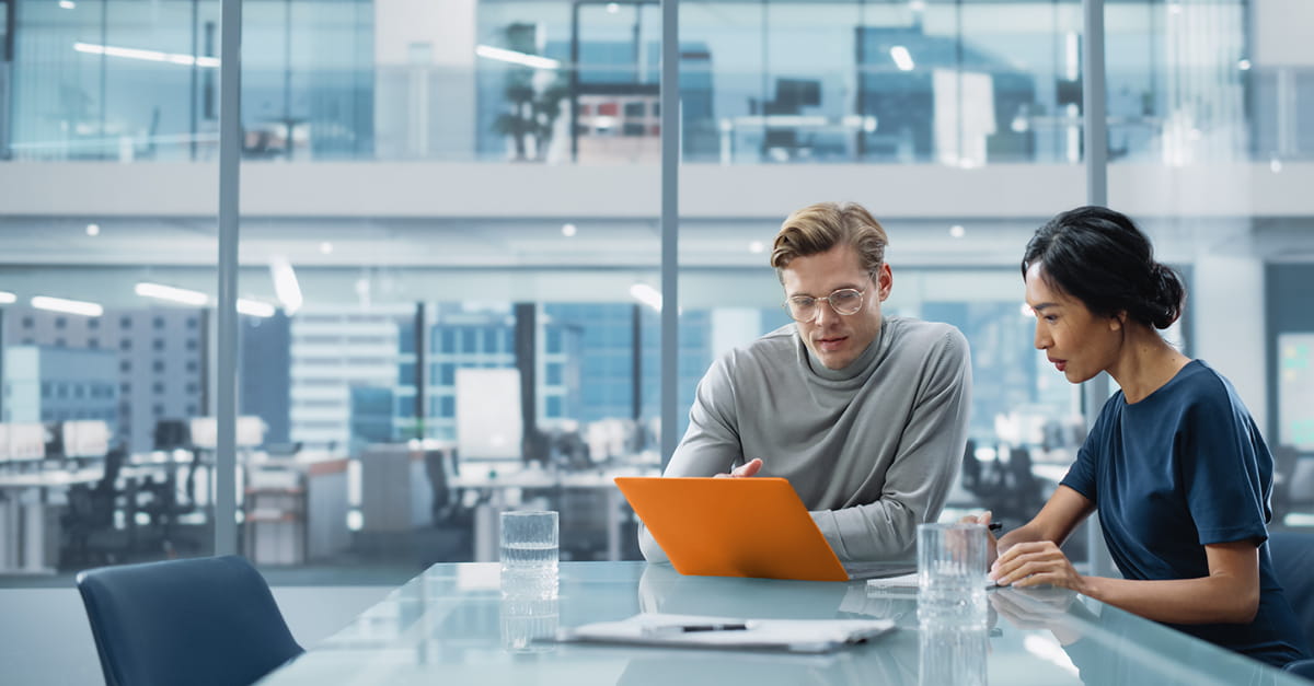 two advisors working together at a desk on a laptop computer